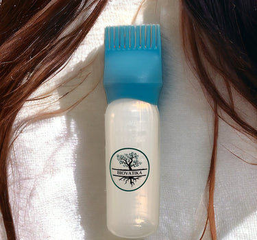 A BIOVATIKA aplikační láhev na vlasy s modrým hřebenovým uzávěrem je zobrazena na dlouhých hnědých vlasech s bílým textilním pozadím.